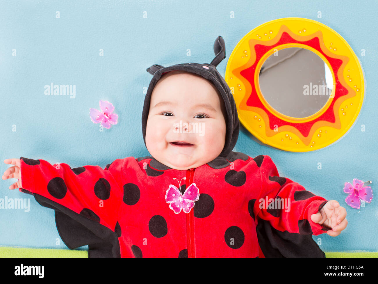 Pretty baby girl, dressed in ladybug costume on green background The