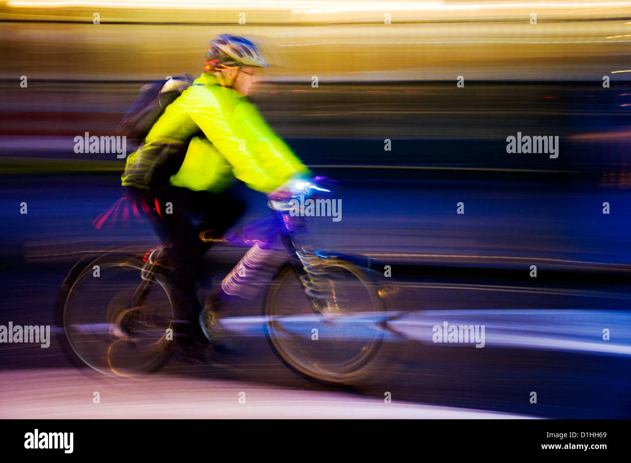 Man riding bicycle at night with lights and hi vis jacket with speed blur Stock Photo