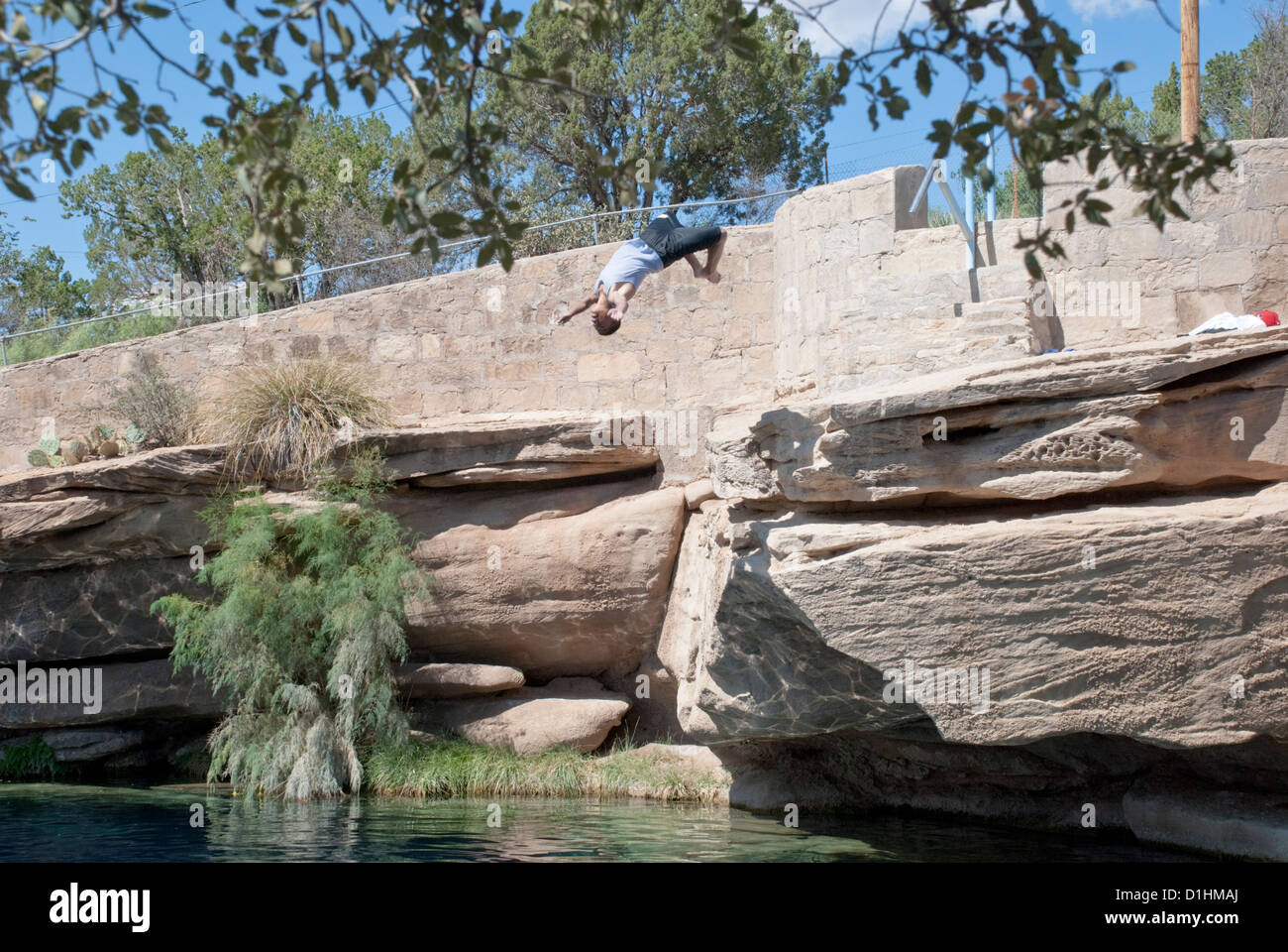 A diver dives backwards off a rock ledge at the famous Blue Hole in Santa Rosa, New Mexico. Stock Photo