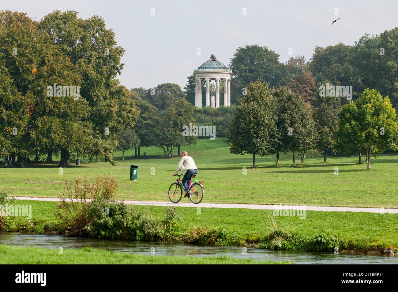 Bicycle rider beside Eisbach with Monopteros in background, Englischer Garten, Munich, Bavaria, Germany Stock Photo