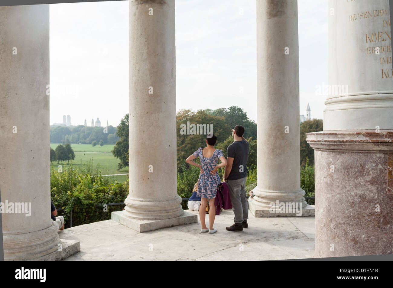 Two people watching the city skyline of Munich from the monopteros in Englischer Garten, Munich, Bavaria, Germany Stock Photo