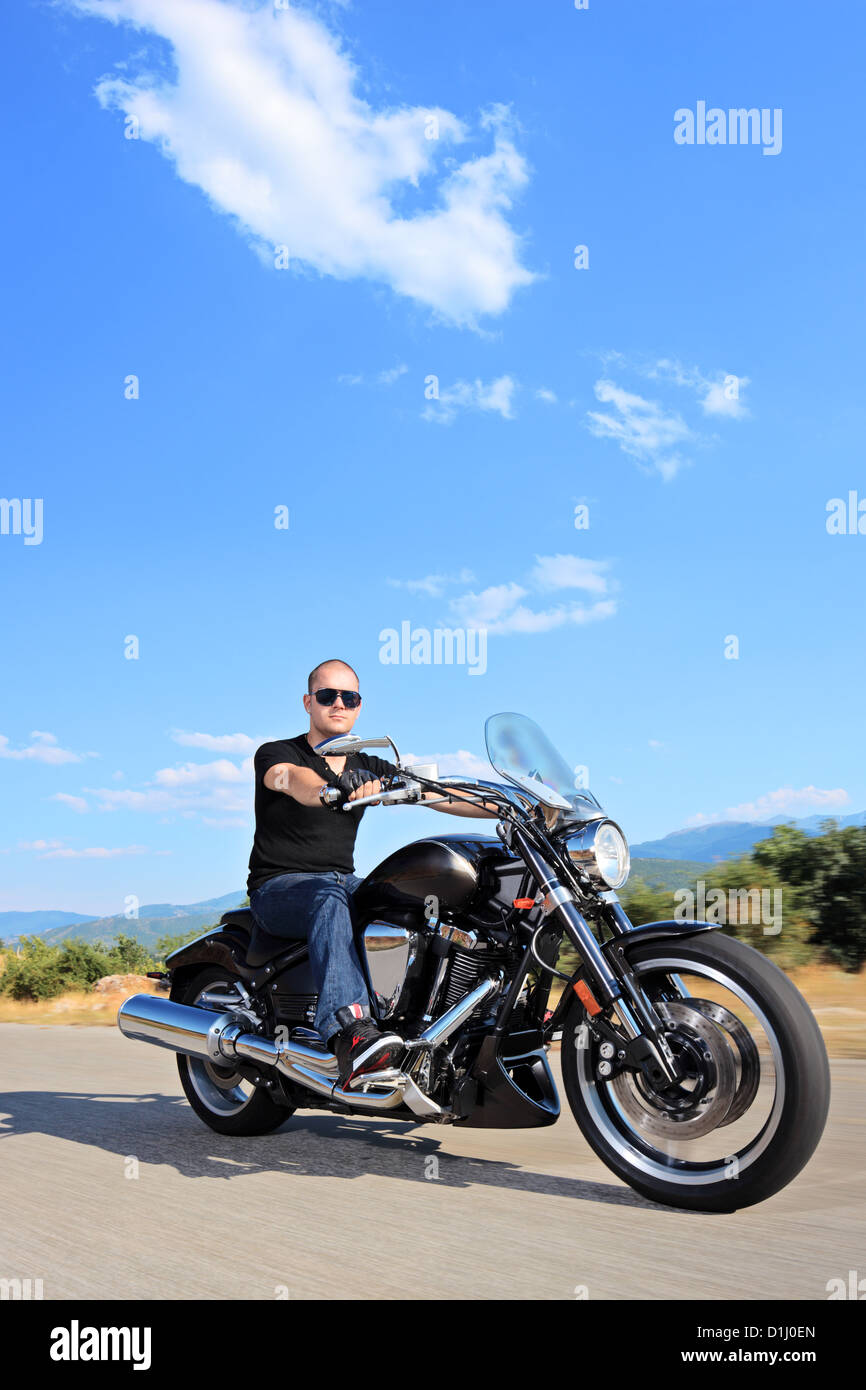 Biker riding a customized motorcycle on an open road Stock Photo