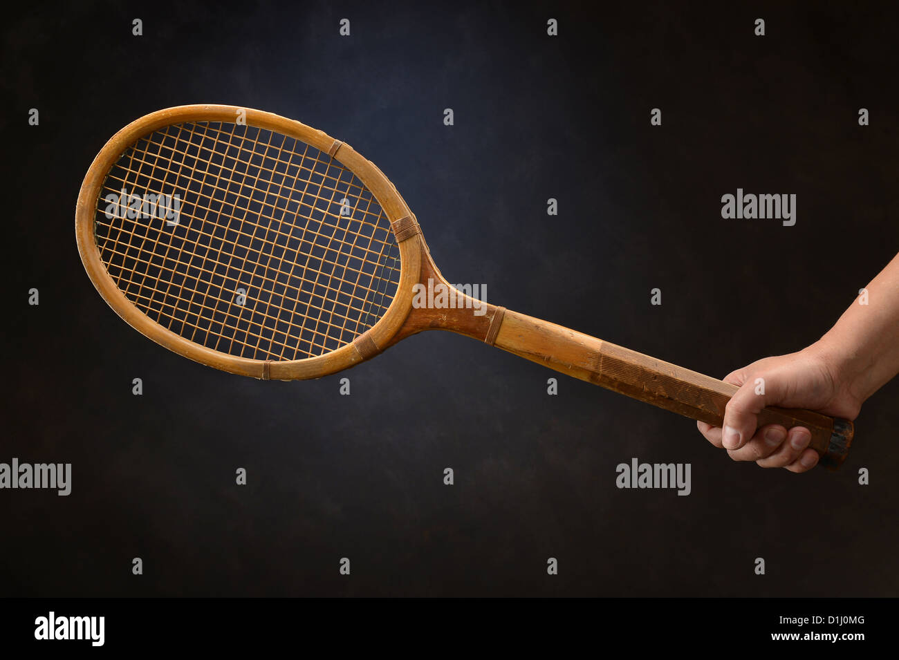 Man's hand holding vintage tennis racket over dark background Stock Photo