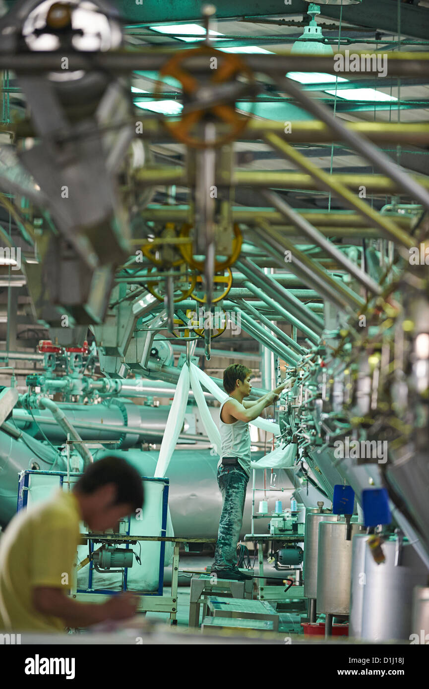 Workers load and unload fabric into large agitating and washing ...
