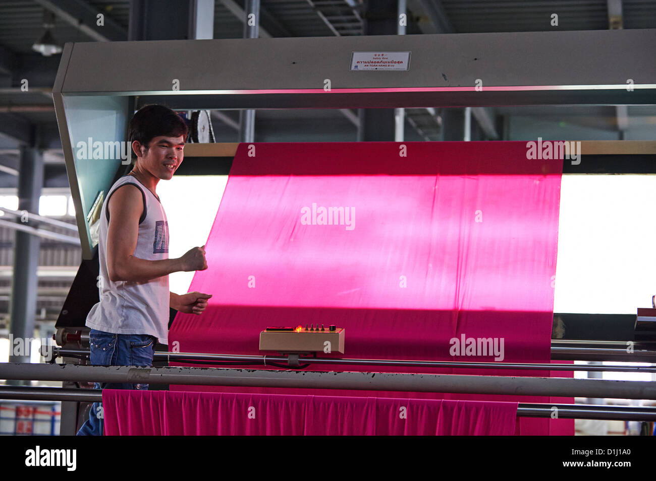 A worker inspects newly dyed fabric for inconstancies and holes Stock Photo
