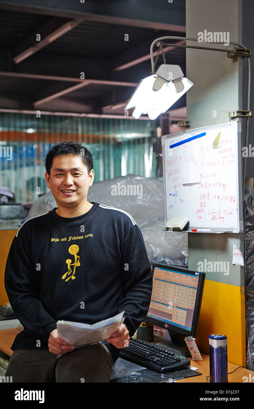 A worker at a textile lab poses next to a computer Stock Photo