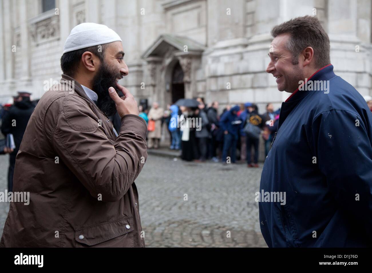 London, UK. 24th December 2012 A member of a radical Muslim group has a debate with a passer by, while people are queuing in the background to get into St Paul's Cathedral.  The group of Muslims had gathered outside the cathedral and set up stalls and handed out leaflets.  There were various complaints to officers from the people queuing nearby to enter St Paul’s Cathedral where they were attending a service. Stock Photo