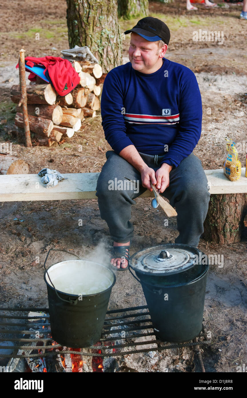 The tourist cooks food for team in a sports camping in the wood Stock ...