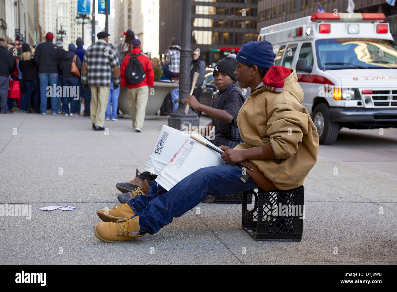 Two street performing young men using plastic buckets as drums