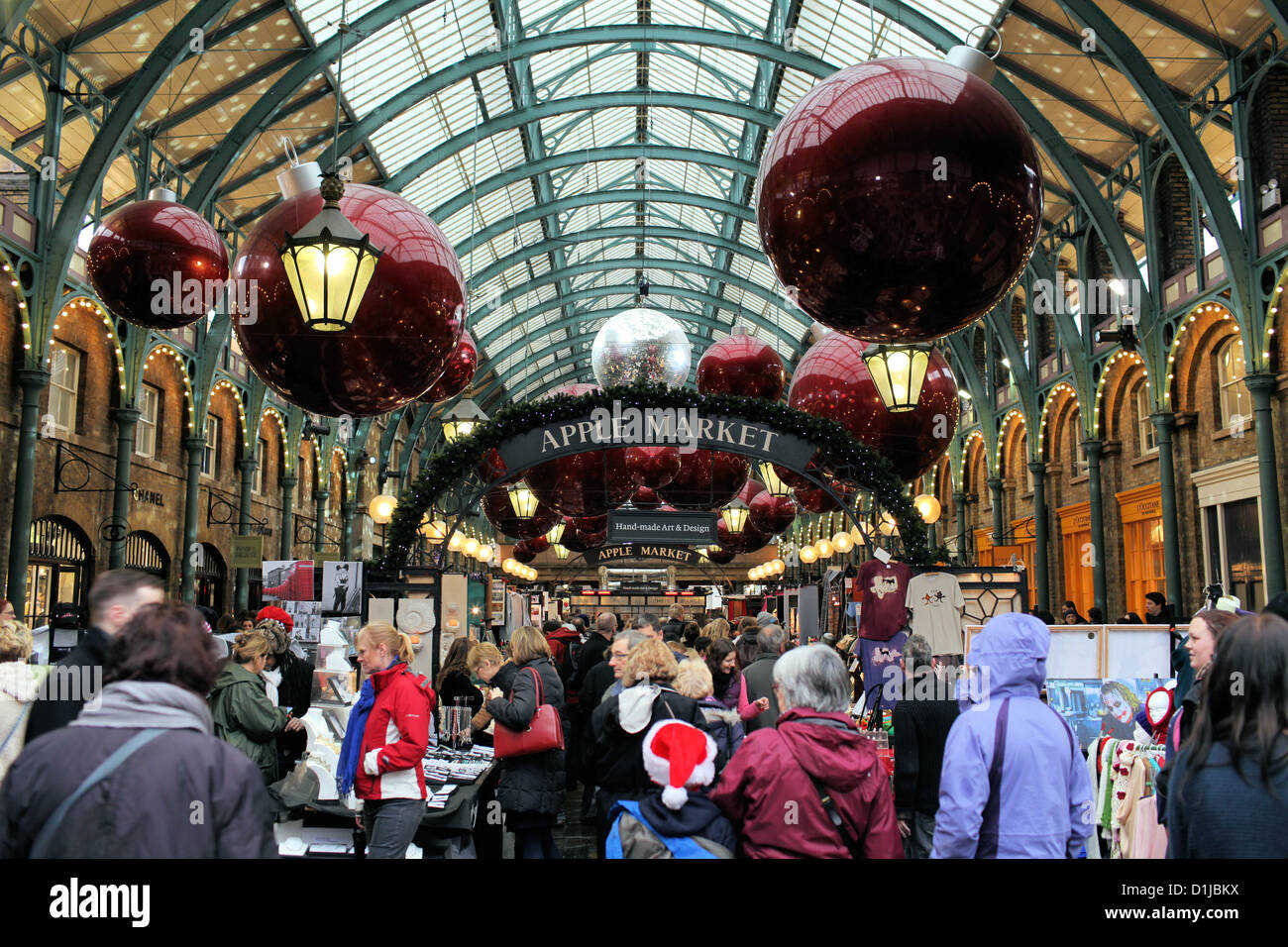 The Apple Market at Covent Garden, London at Christmas.  Crowds wander beneath giant baubles Stock Photo