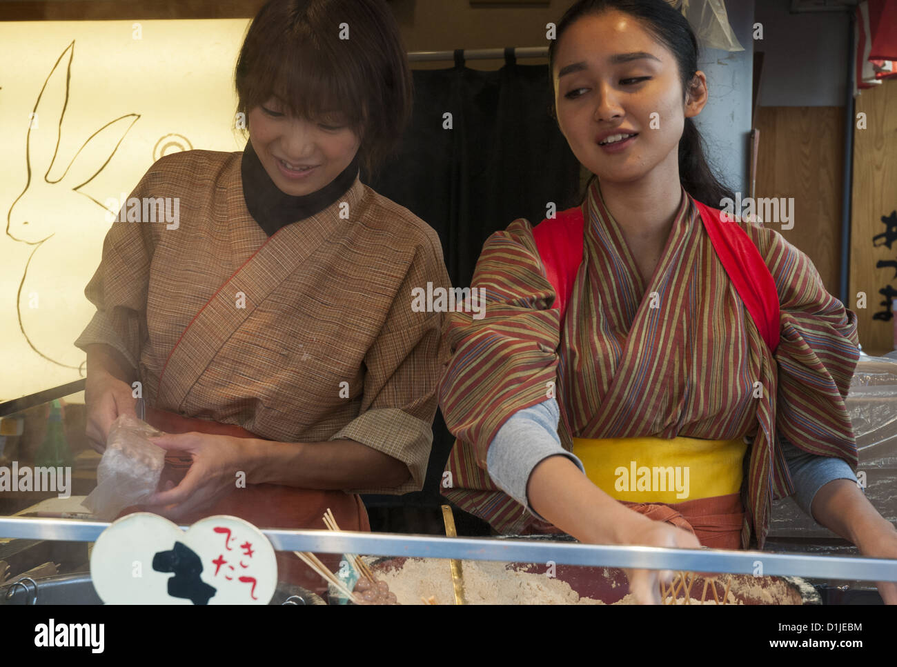 Young women serve up traditional snack foods in the Nakamise shopping street running up to Sensoji Temple in Asakusa, Tokyo Stock Photo