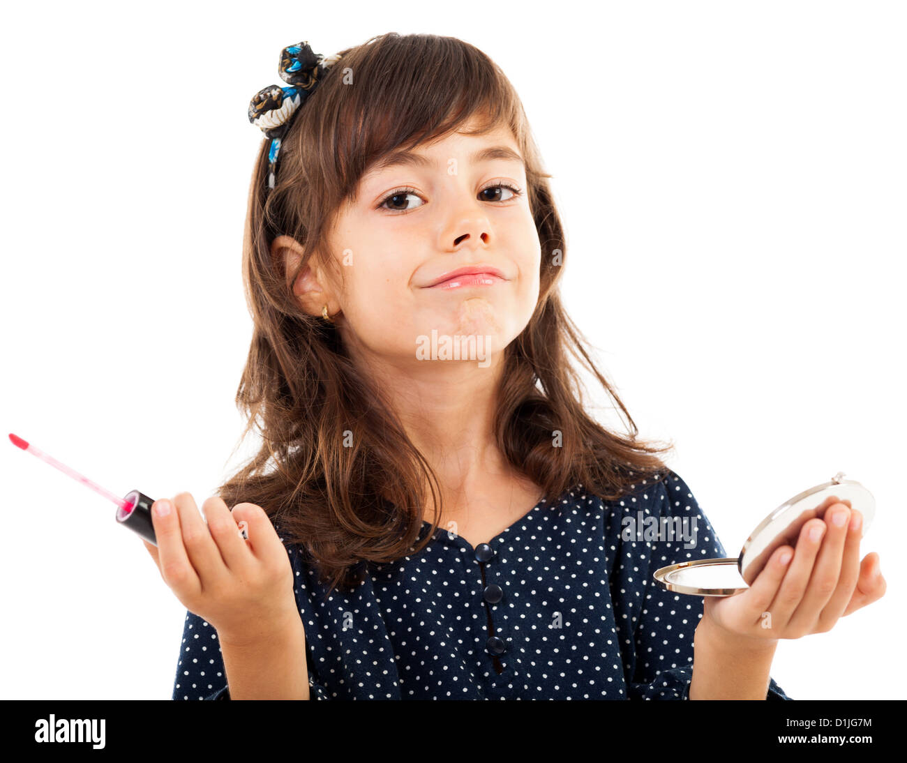 Closeup portrait of a little girl using lipstick while looking in the