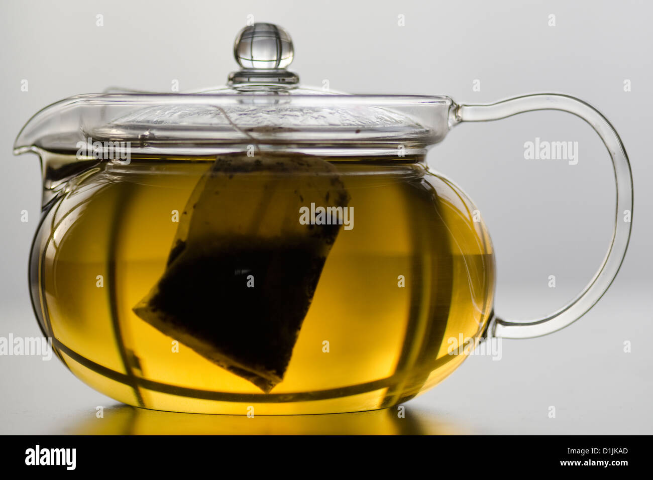Glass tea pot with herb tea bag and herb tea Stock Photo