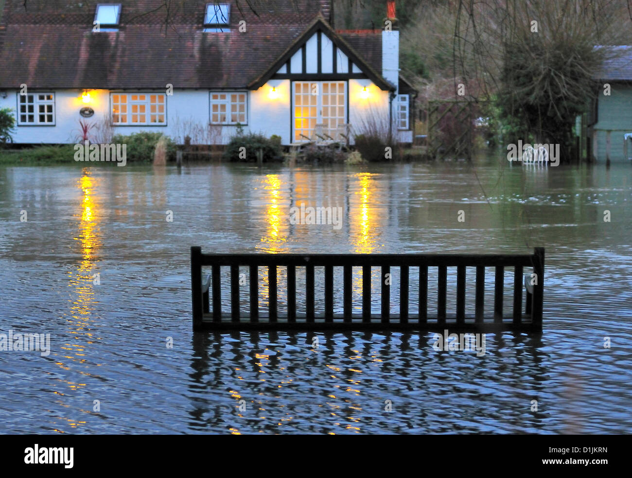 Henley-on-Thames Buckinghamshire   UK   16.00 GMT  20-12-2012 1   Traditional Christmas Day strolls along the Thames side tow path  and feeding the ducks at Mill Meadows ,Henley-on-Thames, thwarted by the rising flood waters (Note  the river Thames is between the bench and the island houses  at Mill Meadow) Stock Photo