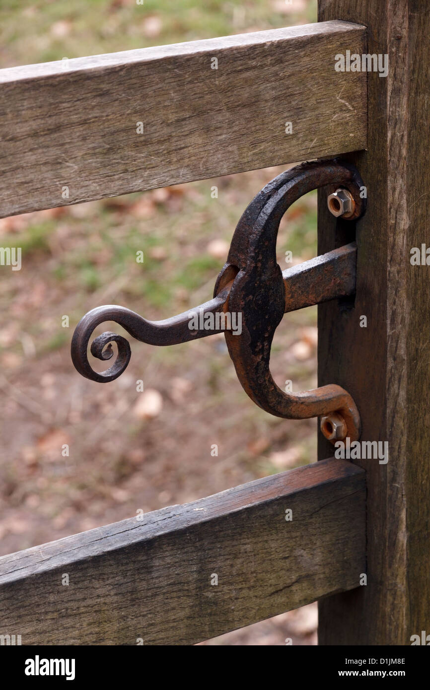 Stylish ornate wrought iron metal wooden gate latch with curves and scroll. Stock Photo