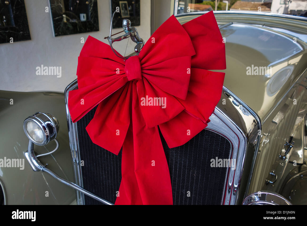 The hood ornament and a red bow for Christmas on the front of a 1929 Pierce Arrow convertible coupe. Stock Photo