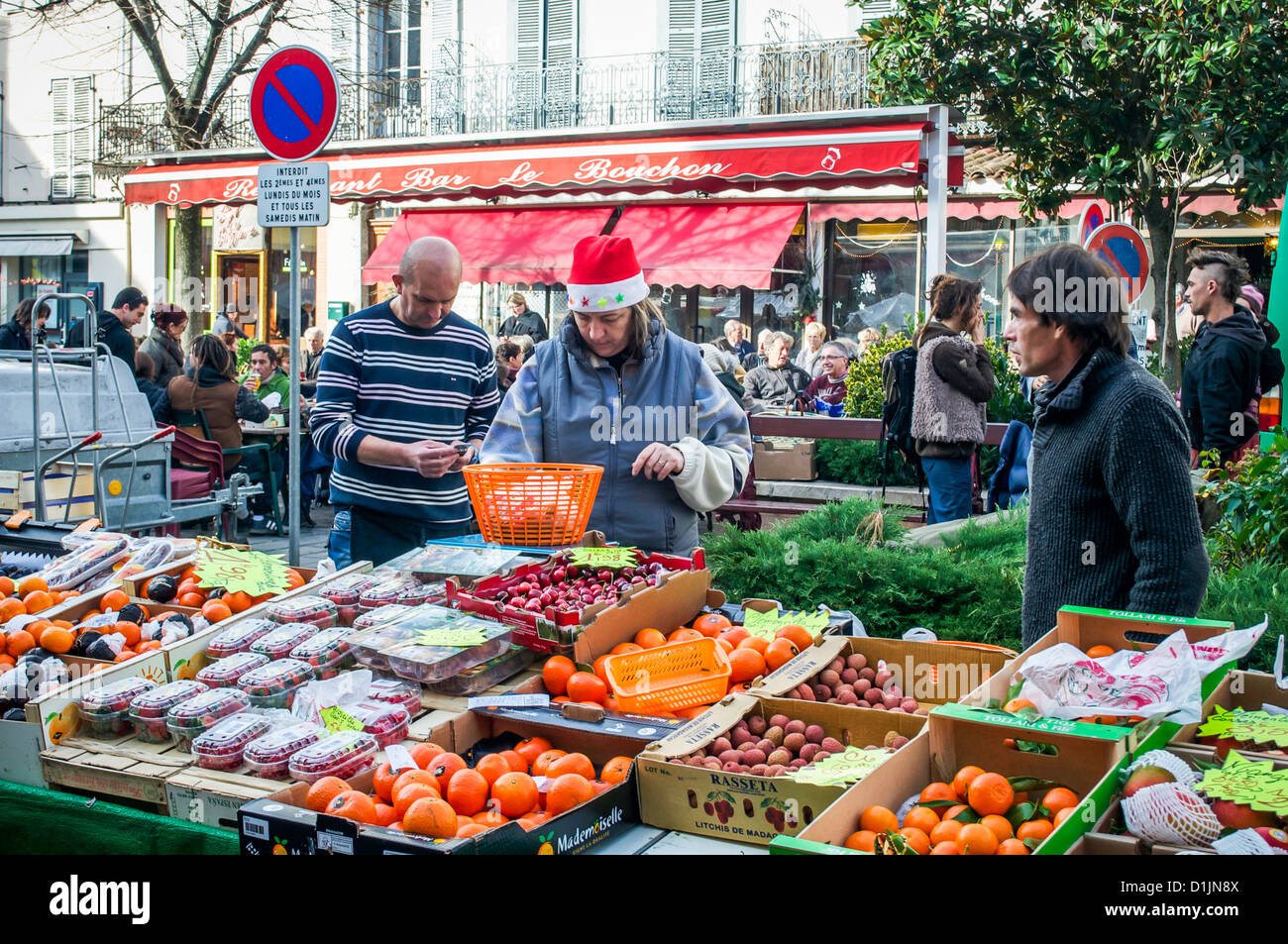 Christmas fruit & vegetable seller wearing a Santa hat at the Saturday market in St. Girons, Midi-Pyrenees, France. Stock Photo
