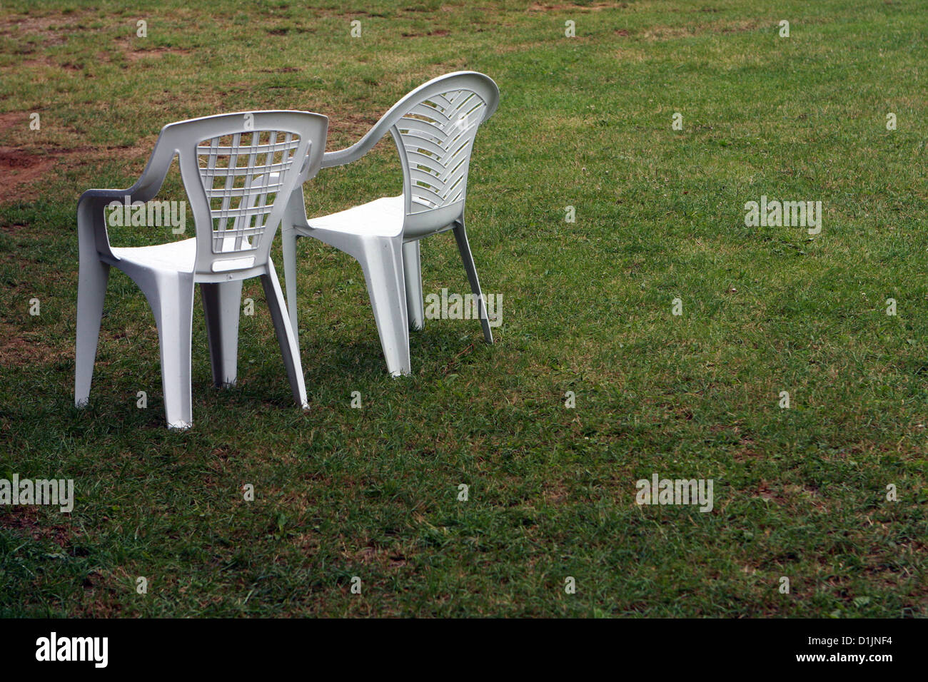 Two empty plastic chairs on grass Stock Photo