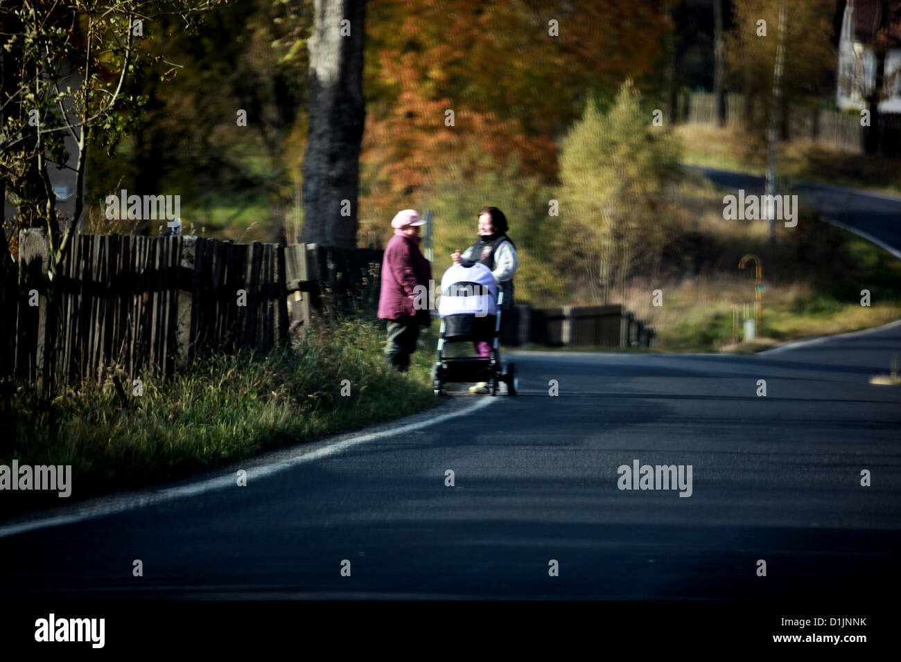 Two women with a pram to walk along the road, roadside, dangerously, autumn rural scenery Stock Photo