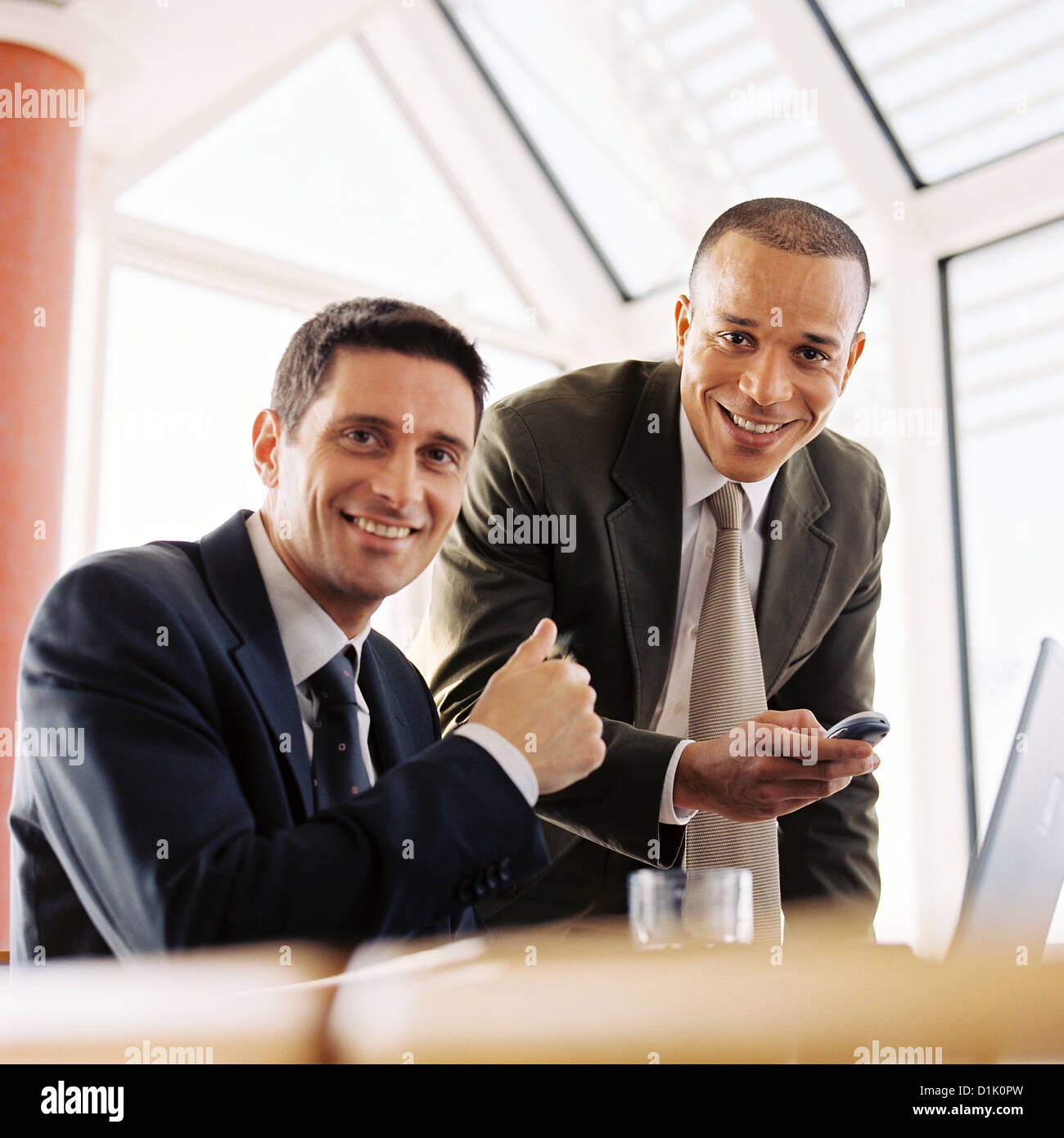 Businessmen in office looking at laptop smiling License free except ads and billboards Stock Photo