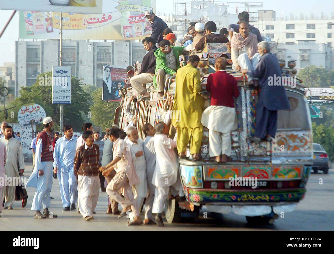 Passengers traveling on an overloaded bus as the shortage  of transportation is being observed in city during strike called by Ahle Sunnat Wal Jamat  (Defunct Sipah-e-Sahaba) against an assassination attack on their leader Aurangzeb Farooqi  convoy and killing of his seven gunmen and driver, at M.A Jinnah Road in Karachi on  Wednesday, December 26, 2012. Stock Photo