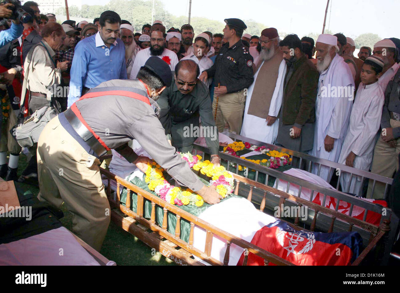 Police officials lay floral wreath upon coffin of police  officials, who killed in an assassination attack on Ahle Sunnat Wal Jamat (Defunct Sipah-e- Sahaba) leader Aurangzeb Farooqi convoy, after their funeral prayer at Police Lines Garden  Headquarter in Karachi on Wednesday, December 26, 2012 Stock Photo