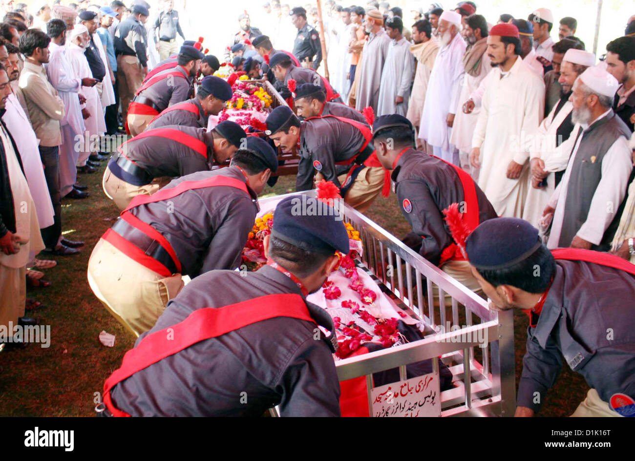 Police officials holding up coffin of police officials, who  killed in an assassination attack on Ahle Sunnat Wal Jamat (Defunct Sipah-e-Sahaba) leader  Aurangzeb Farooqi convoy, to laid them rest after their funeral prayer at Police Lines Garden  Headquarter in Karachi on Wednesday, December 26, 2012. Stock Photo