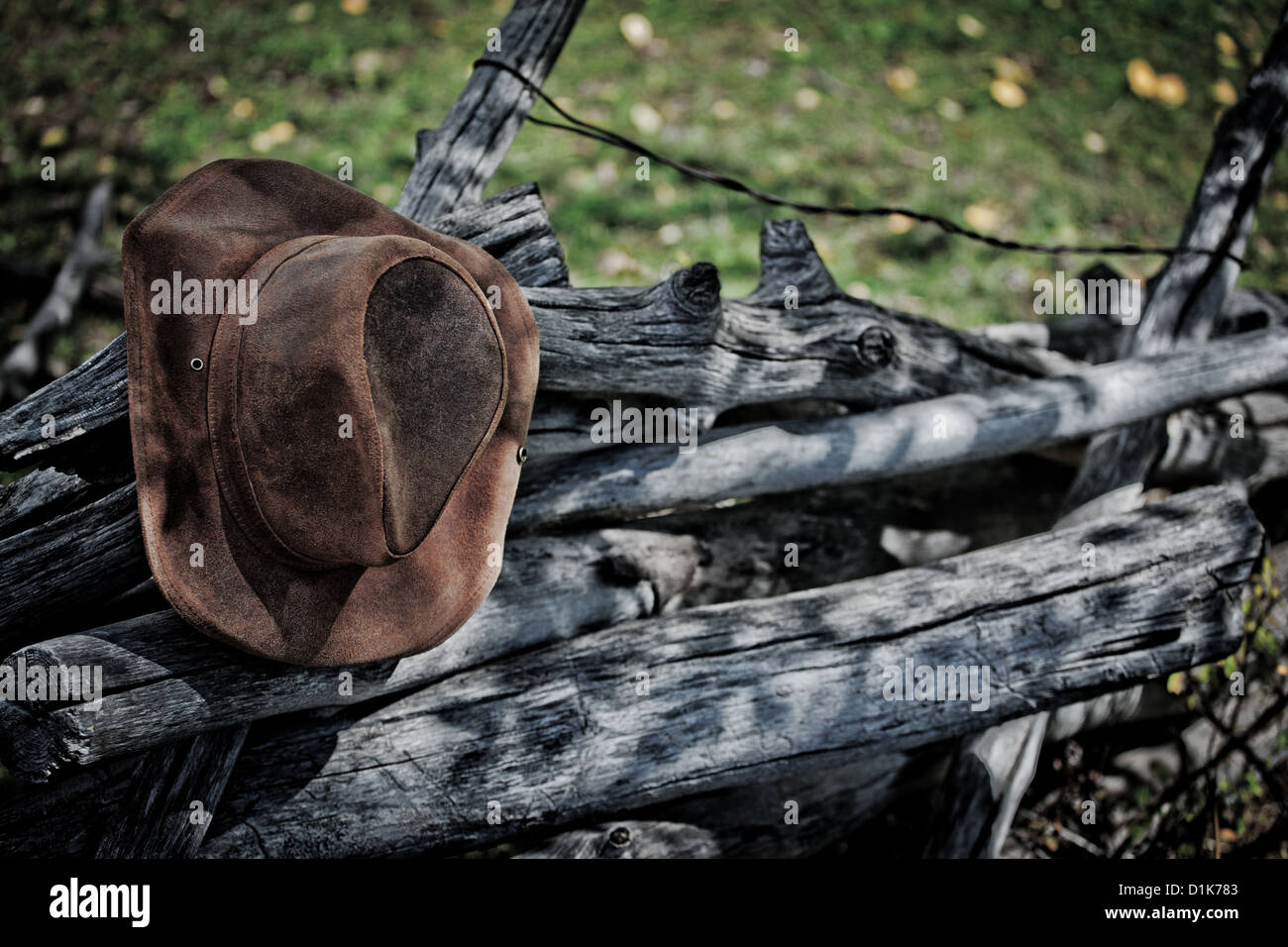 Leather cowboy hat hanging on rustic old log fence Stock Photo