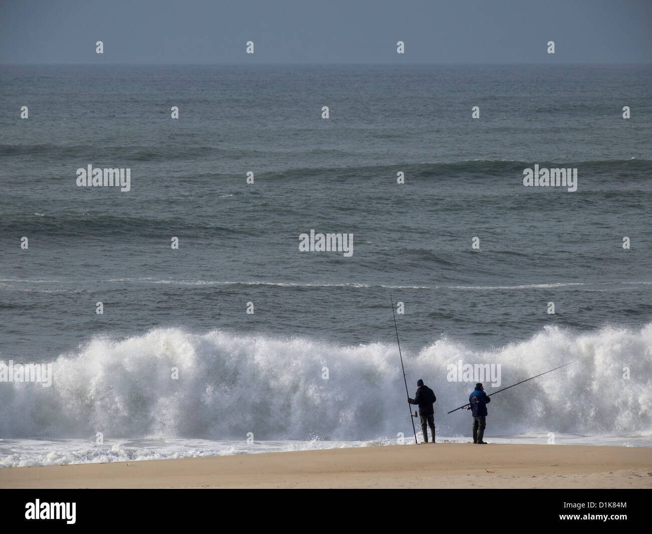 Two people surf fishing in sea shore Stock Photo