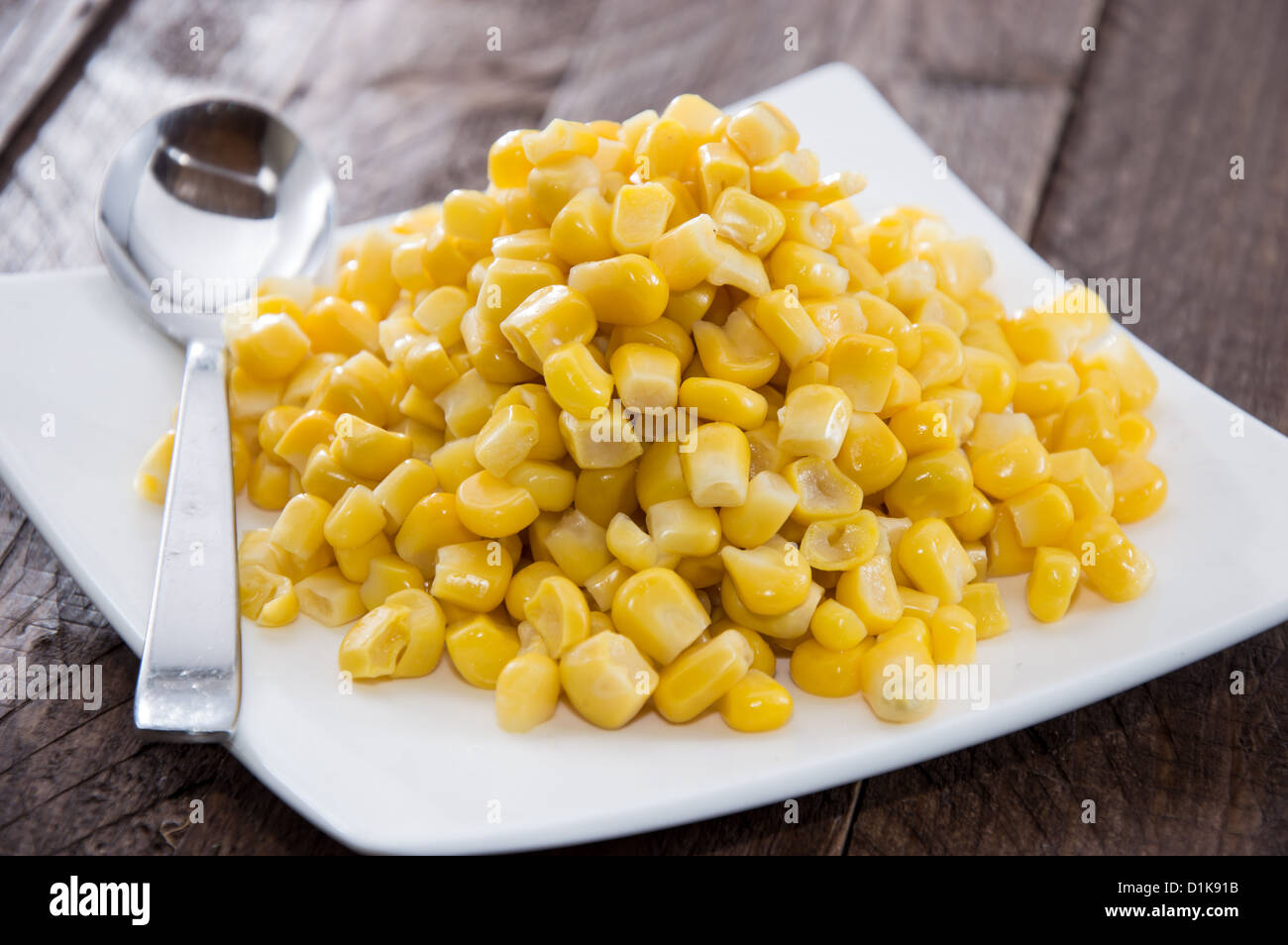 Plate with Corn on wooden background Stock Photo