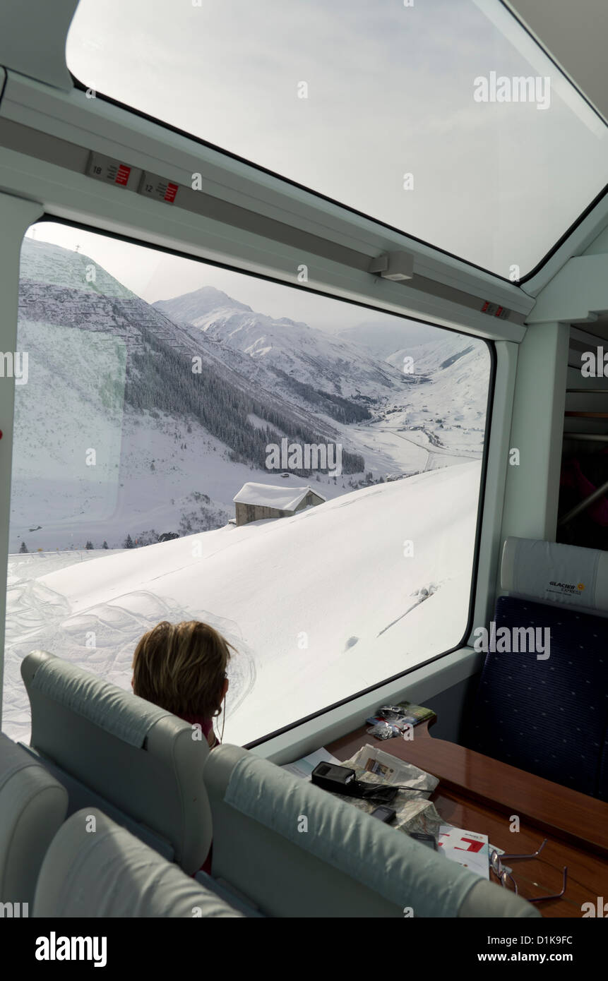 A passenger on the Glacier Express Train looks out onto the mountains near Andermatt, Switzerland Stock Photo