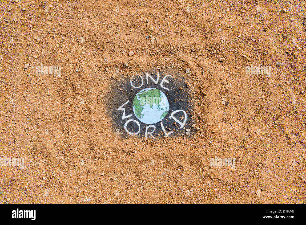 Chalkboard with the earth and ONE WORLD written on it on a dirt track. India Stock Photo