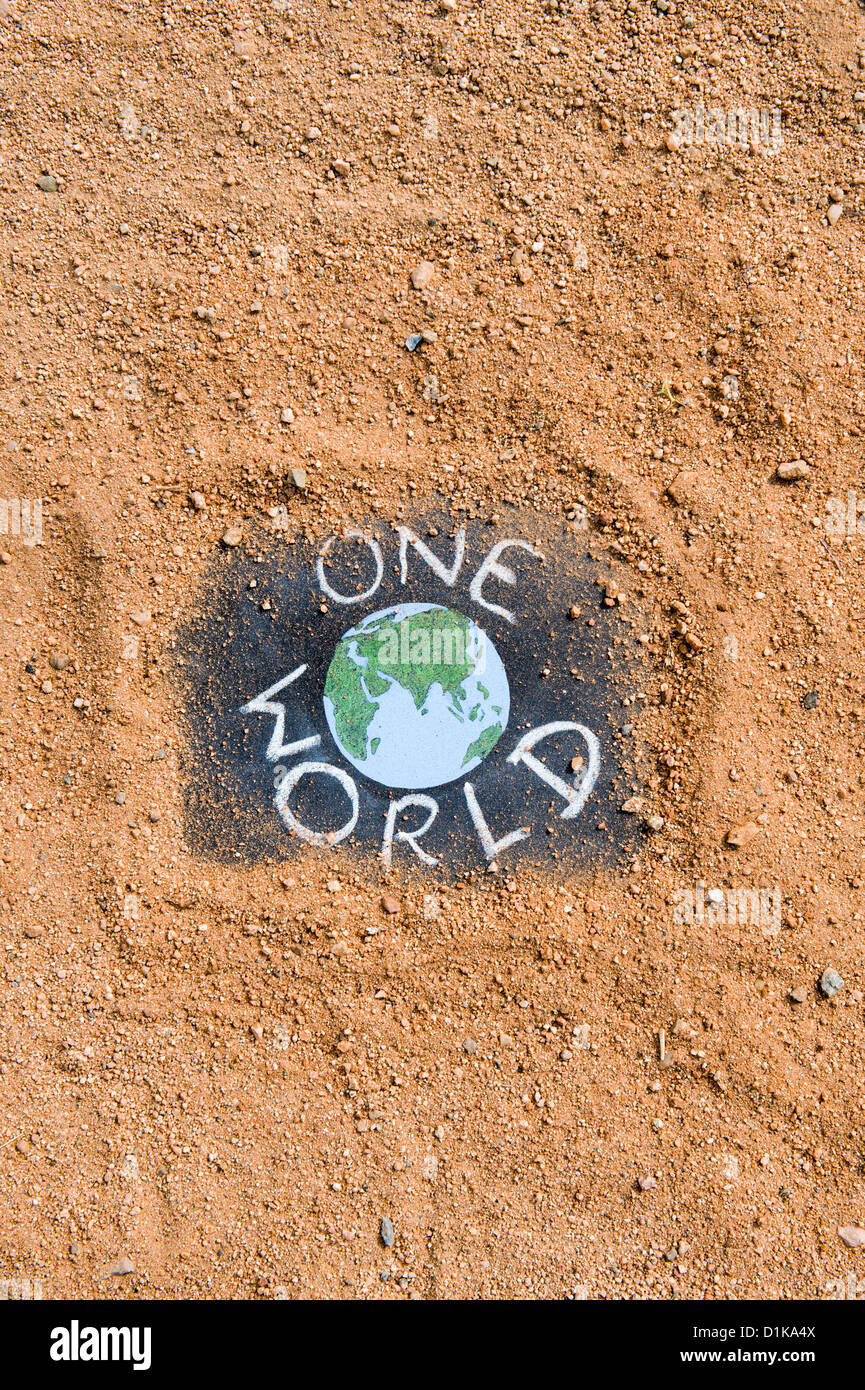 Chalkboard with the earth and ONE WORLD written on it on a dirt track. India Stock Photo