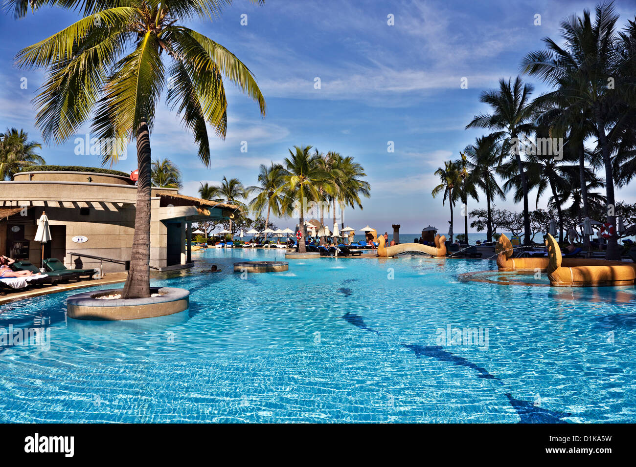 Swimming pool and sunbathing area, complete with tropical palms, at the