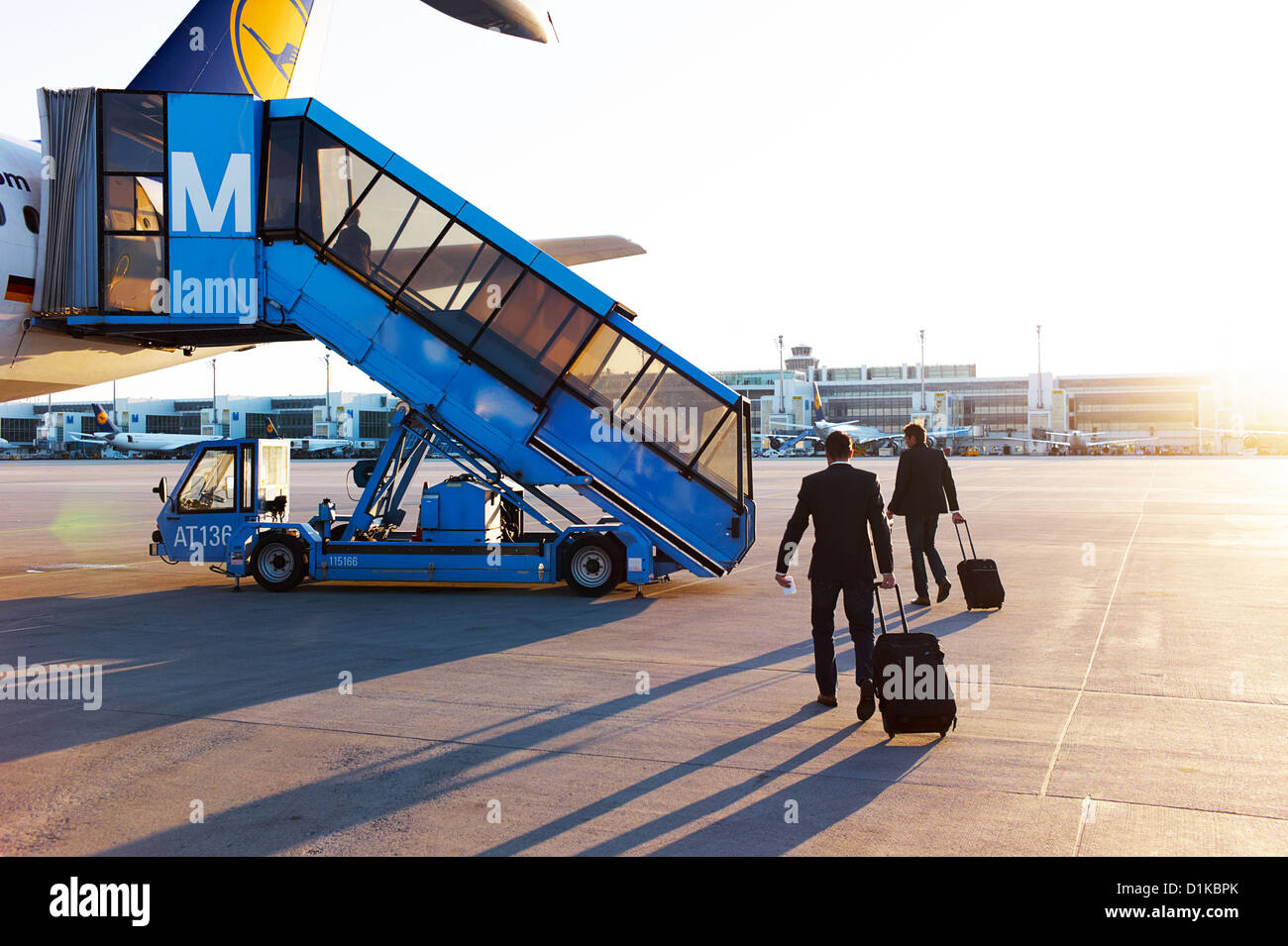Businessmen and travelers board a plane on the tarmac at sunset Stock ...