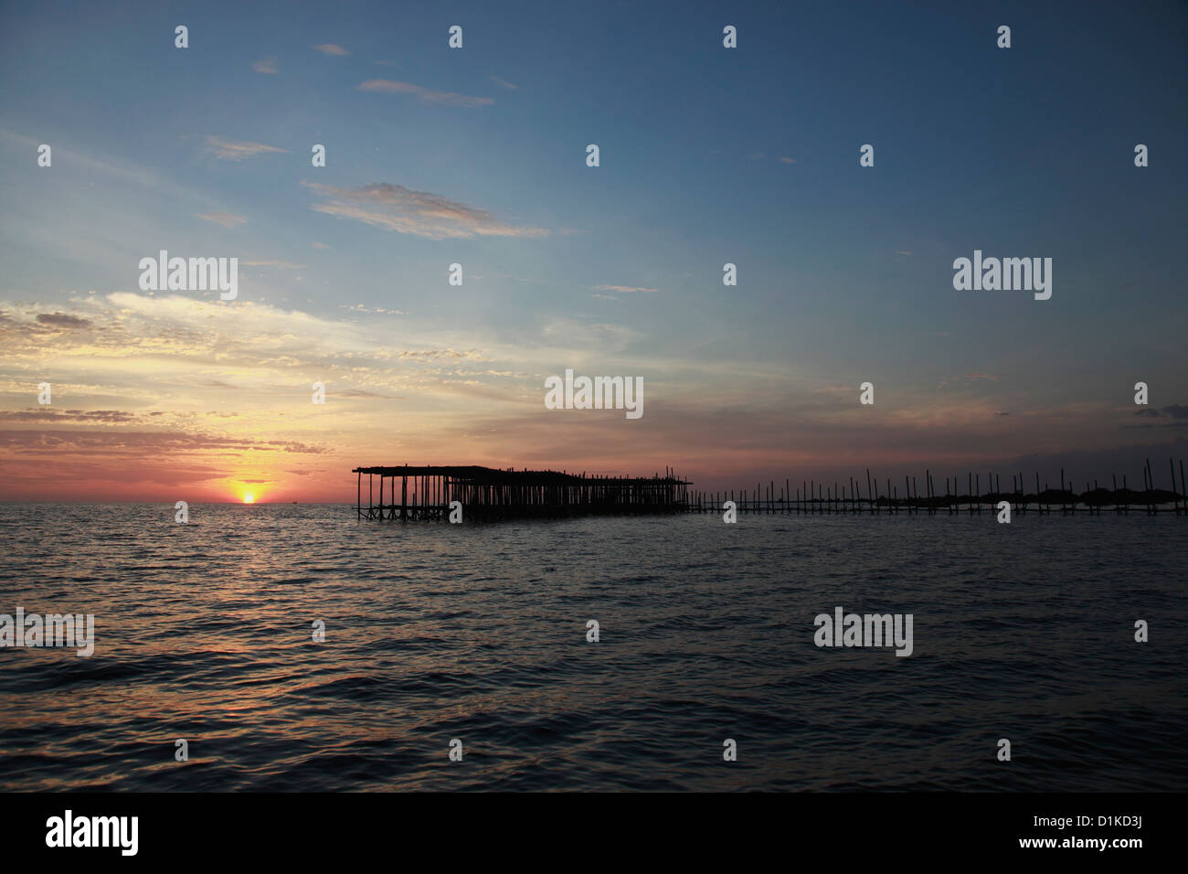 Sun setting in the ocean with pier in foreground, Cambodia Stock Photo