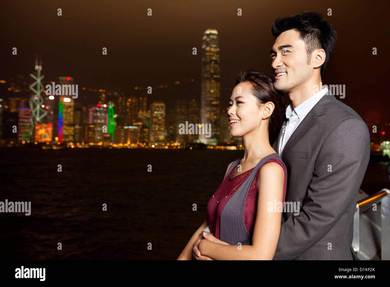 Happy young couple enjoying the night view of Victoria Harbor, Hong ...
