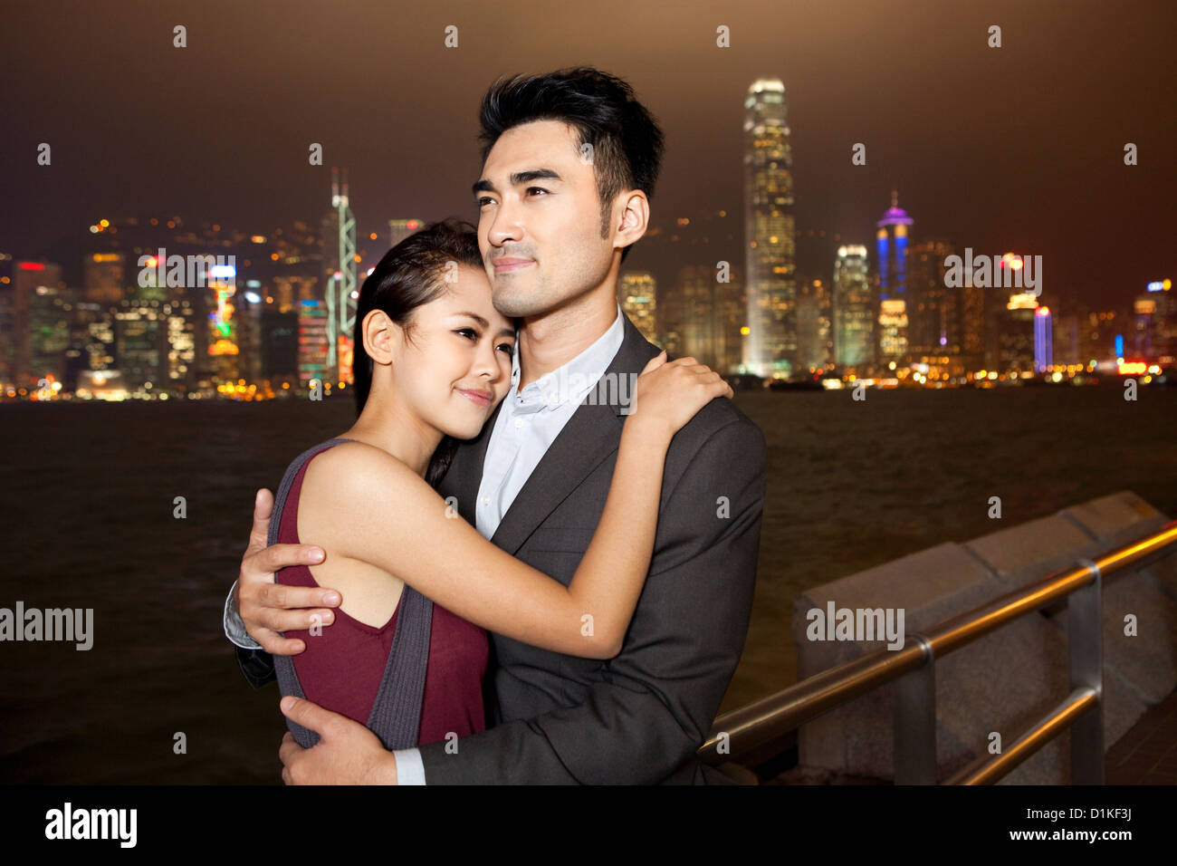 Happy young couple enjoying the night view of Victoria Harbor, Hong ...