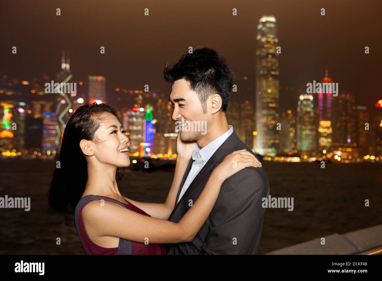 Happy young couple enjoying the night view of Victoria Harbor, Hong ...