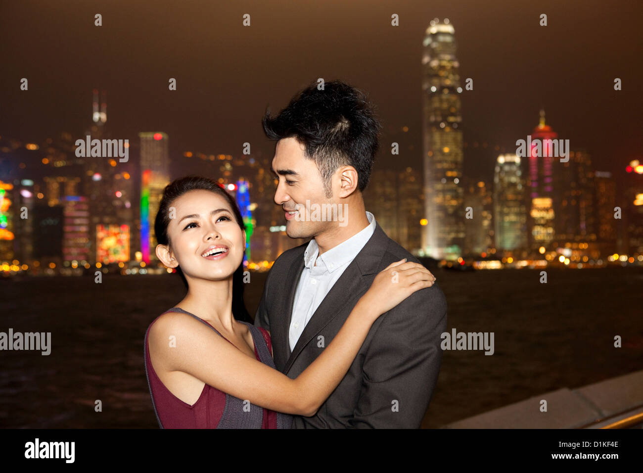 Happy young couple enjoying the night view of Victoria Harbor, Hong ...