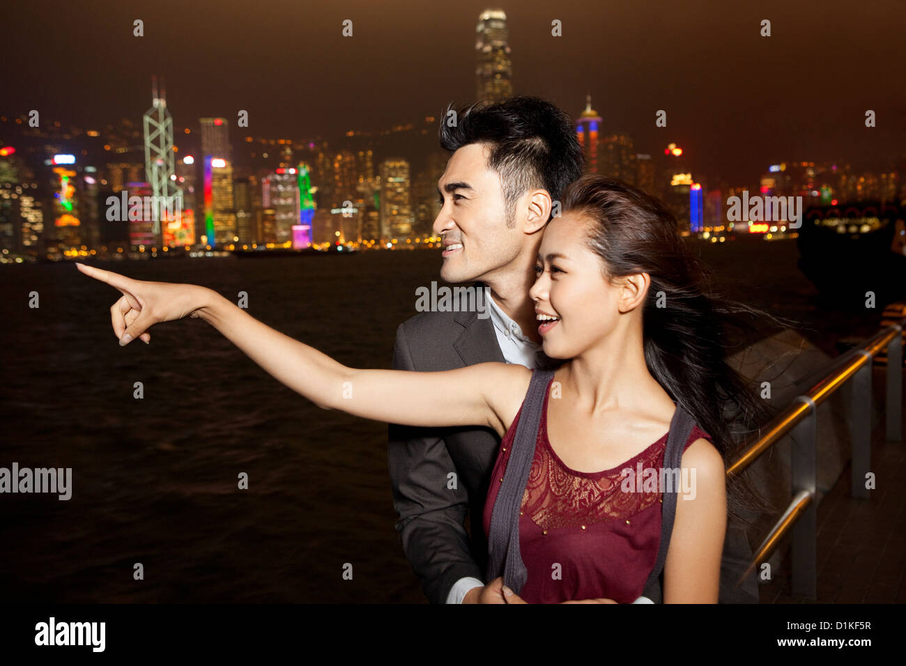 Happy young couple enjoying the night view of Victoria Harbor, Hong ...