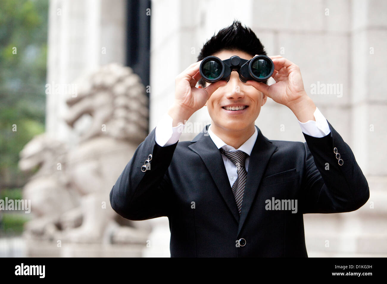 Smiling young businessman looking through binoculars outdoors, Hong Kong Stock Photo Alamy