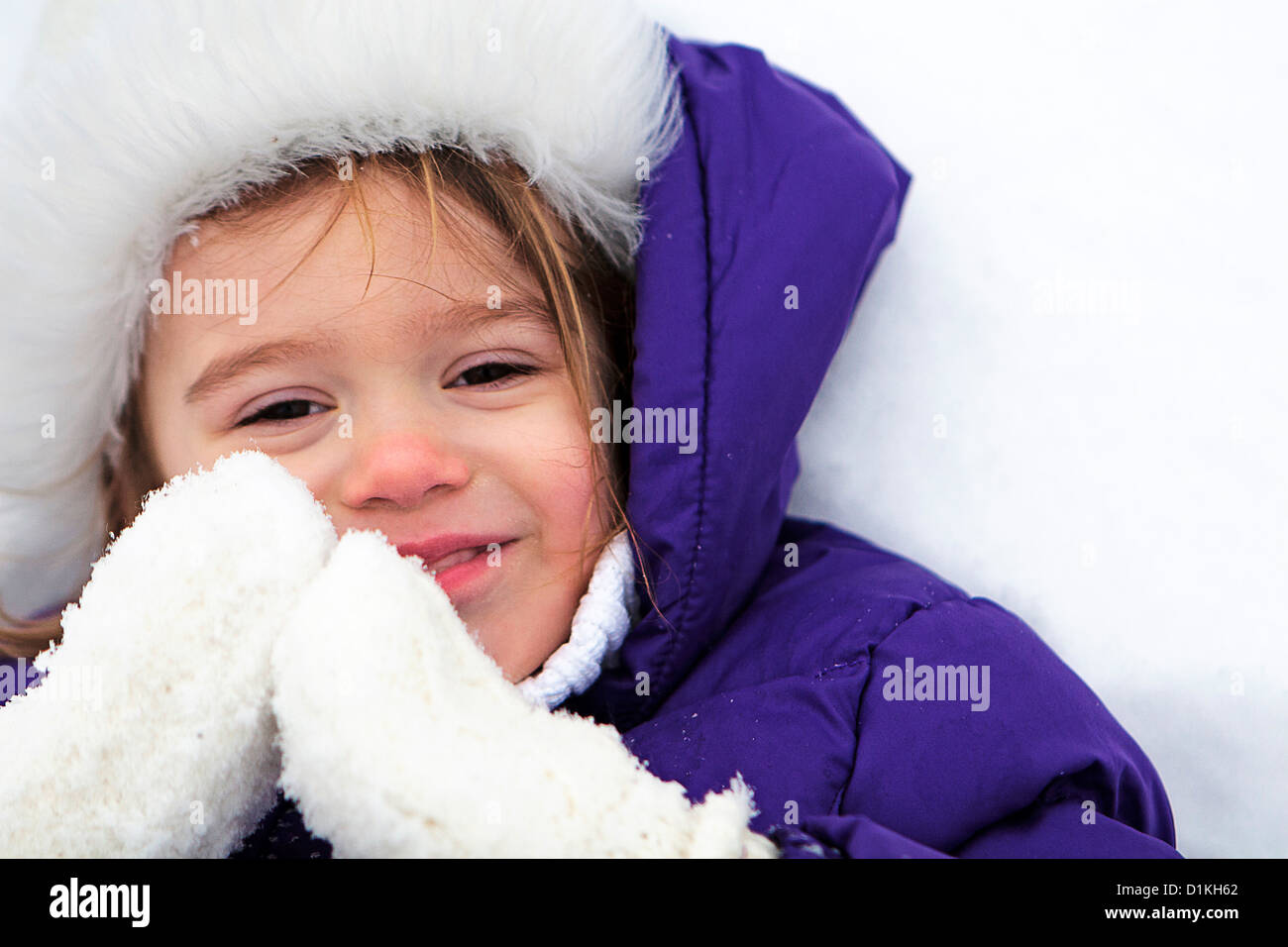 Smiling girl lying in the snow Stock Photo - Alamy