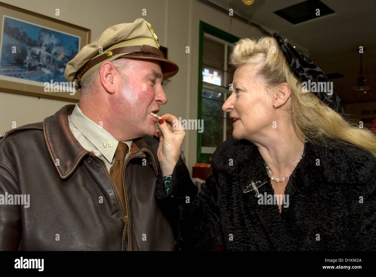 A forces sweetheart feeding a biscuit to her US airforce partner at a world War Two re-enactment day, Boxing Day Stock Photo