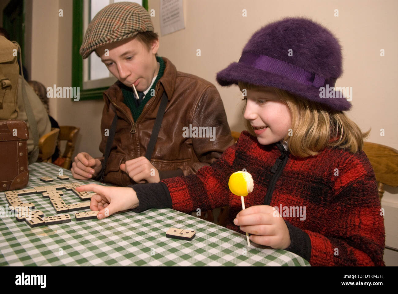 7 yr old girl and 12 yr old boy playing dominoes on Boxing Day (26 Dec 2012) at a railway station cafe dressed in 1940s attire Stock Photo