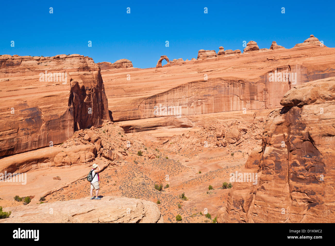 Female tourist looking up towards Delicate Arch from in Arches National Park near Moab Utah USA United states of america Stock Photo