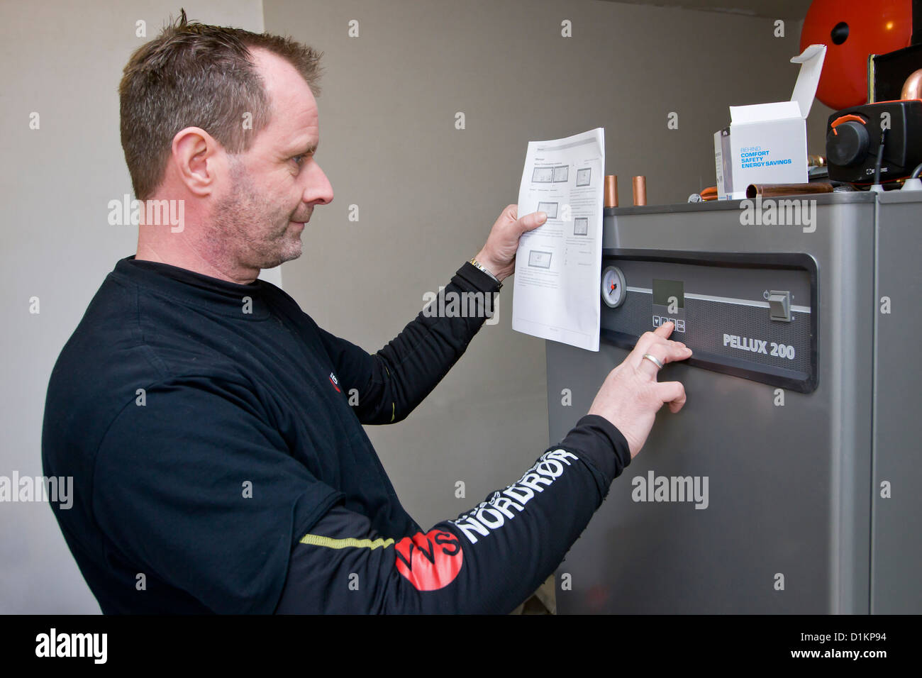 A plumber is adjusting a boiler Stock Photo