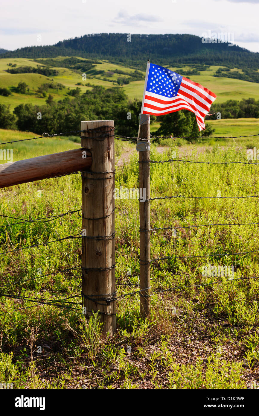 A modest American flag taped to a ranch fence in rural Wyoming snaps in the wind. Stock Photo