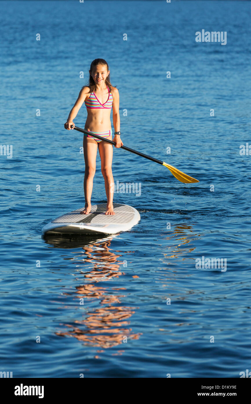 Mixed race girl paddle boarding Stock Photo