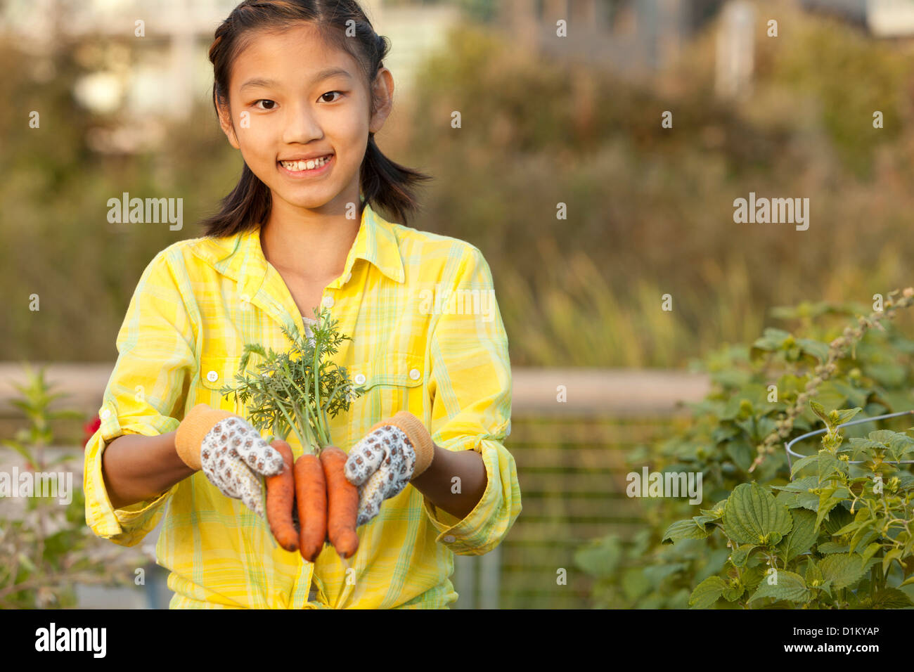 Japanese girl holding bunch of carrots Stock Photo